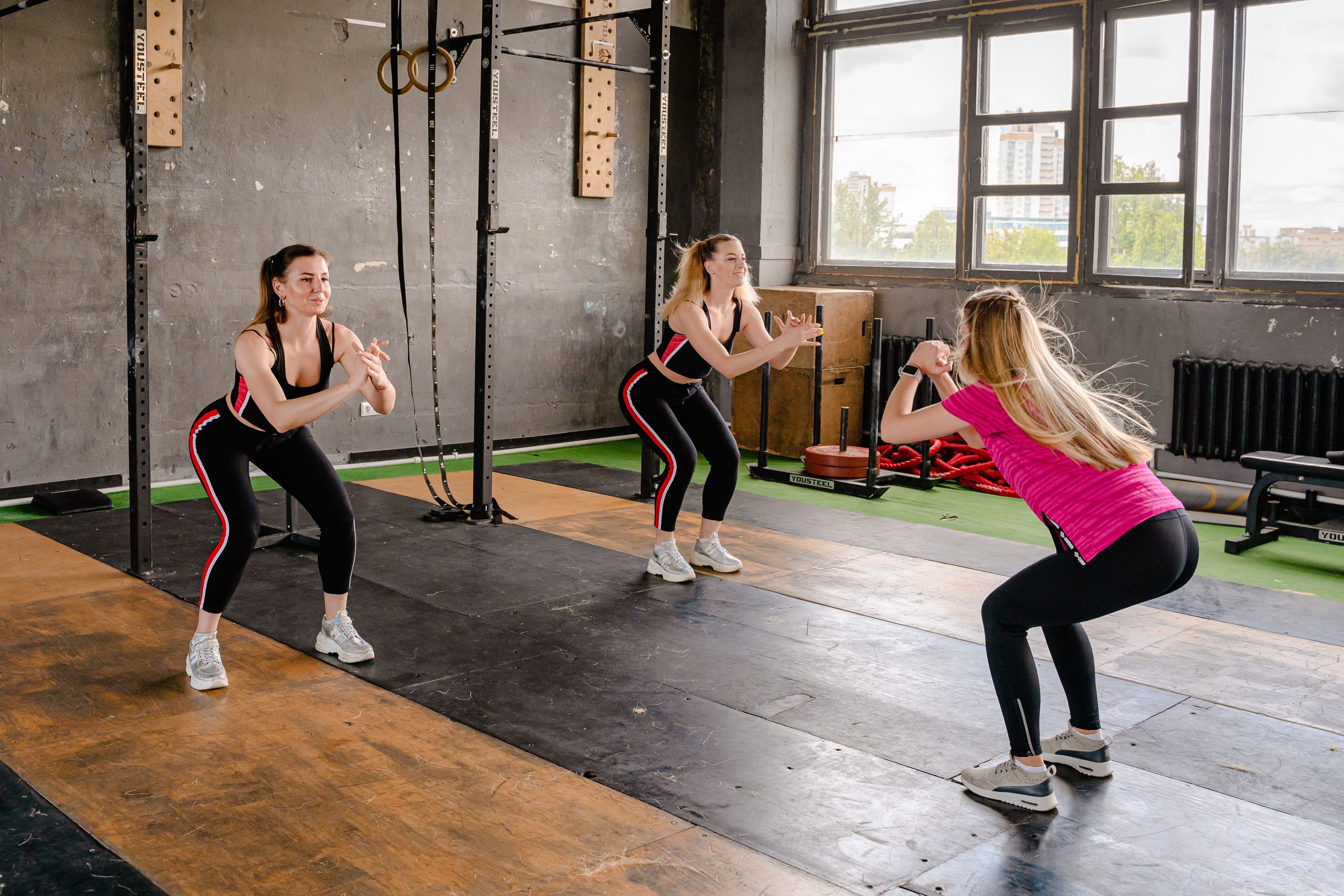 Small group of clients doing bodyweight squats together in a gym