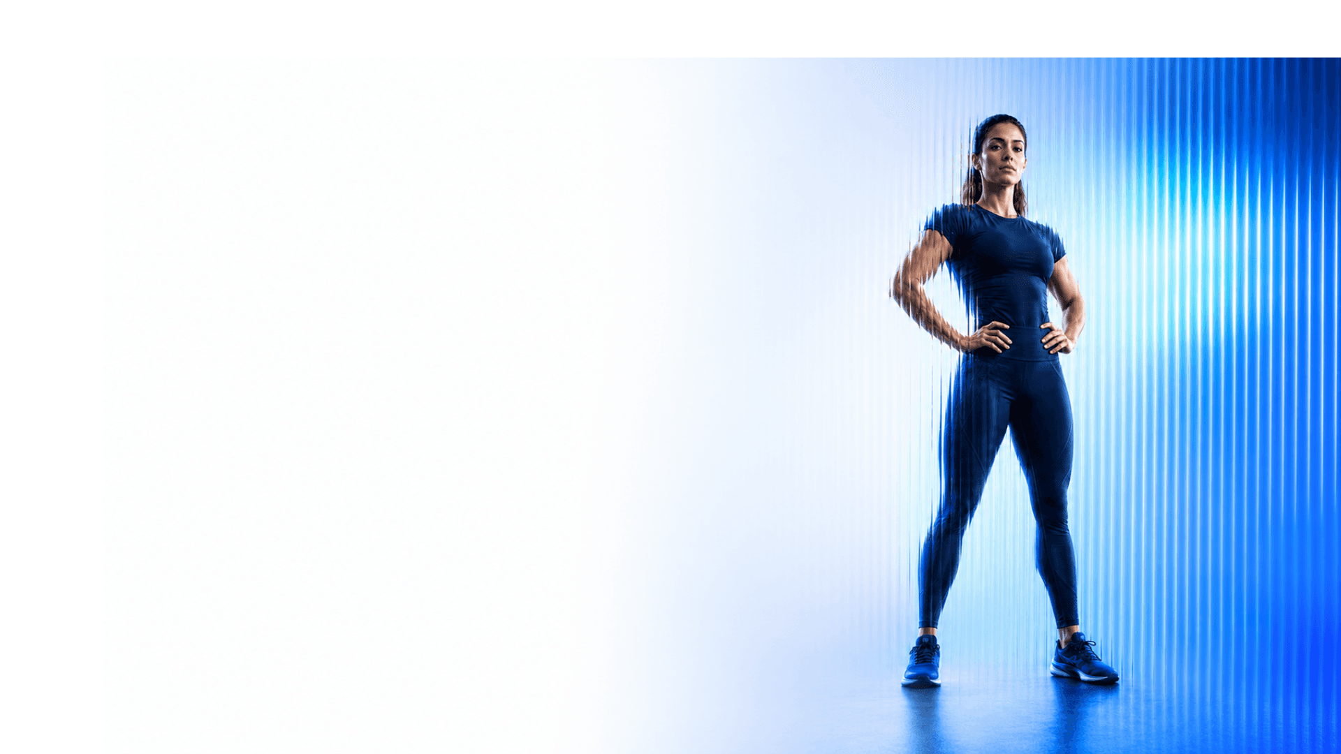 Female trainer standing on the right against blue fluted glass light