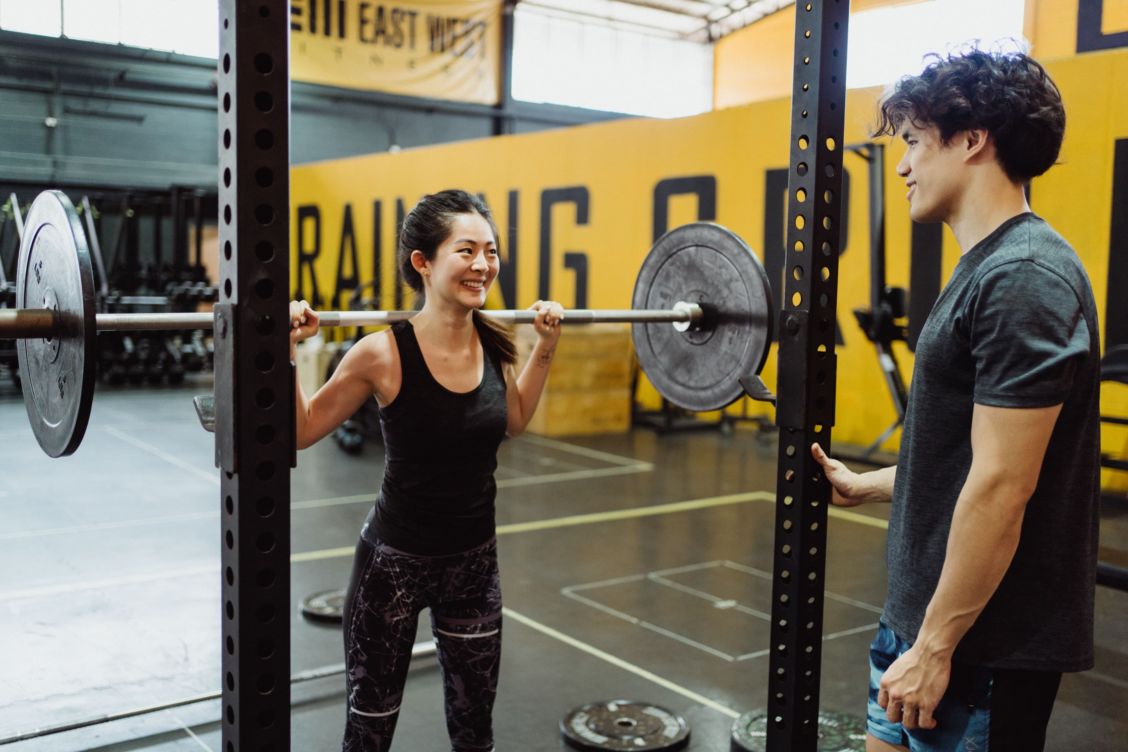 Trainer coaching a client through a back squat in the gym